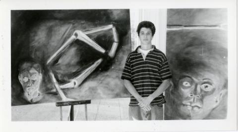 Student posing with paintings