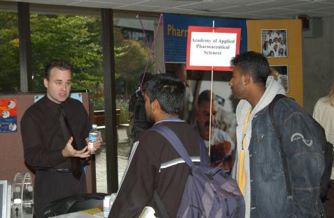 Students Speak with Presenter at Academy of Applied Pharmaceutical Sciences Table, Graduate & Professional Schools Fair, the Meeting Place