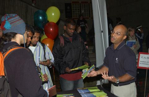 Students talk with Presenter at Table, Graduate & Professional Schools Fair, the Meeting Place