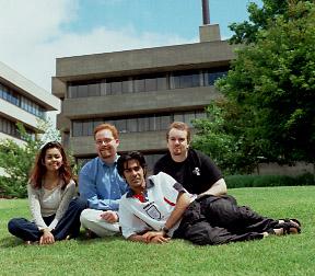 Four Students Sit on Lawn, H-Wing Patio, Promotional Image