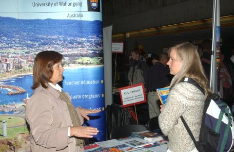 Student talks with Presenter at Table, Graduate and Professional Schools Fair, the Meeting Place