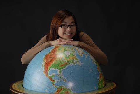 Student Poses with Floor Globe in Wooden Frame, Promotional Image