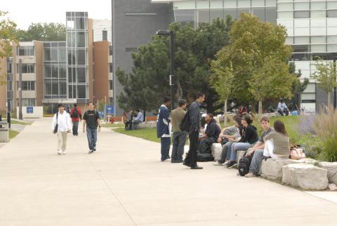 Students on Pathway, Some Seated on Landscaping Rocks, between H-Wing and Management Building (MW)