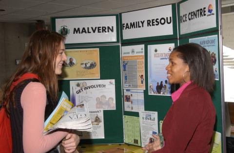Student Speaks with Presenter at Malvern Family Resource Centre Table, Volunteer Fair, the Meeting Place