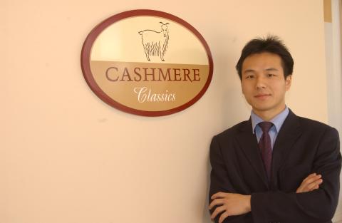 Rocky Zhou, Management and Economics Alumni, Photographed with Sign for his Brand "Cashmere Classics".