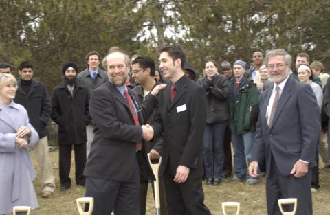 Tom Nowers Shakes Hands with Dan Bandurka, Rose Patten and Paul Thompson Standing Nearby, Groundbreaking Event for Student Centre, Outdoors on Site