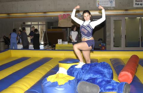 Cheerleader Poses with Defeated Boston Pizza Mascot, Inflatable Joust Arena Game, Spirit Day, the Meeting Place