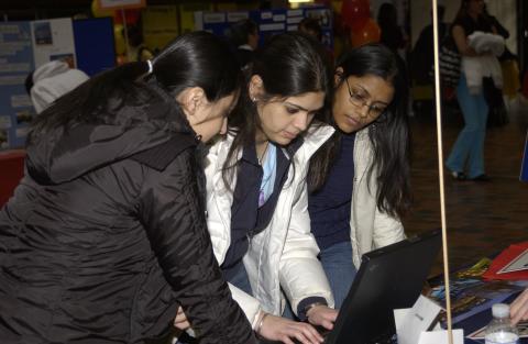 Three Students Look at Material at Table, Volunteer Fair, the Meeting Place