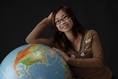 Student Poses with Floor Globe in Wooden Frame, Promotional Image