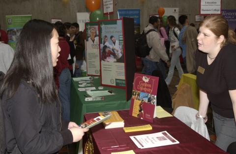 Student talks with Presenter at Gannon University Table, Graduate & Professional Schools Fair, the Meeting Place