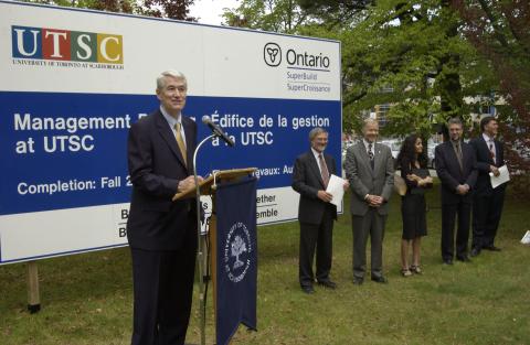 Robert Birgeneau Speaks, Other Dignitaries Stand in Line in front of Project Signage, on Site, Groundbreaking, Management Wing (MW)