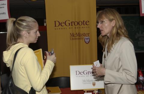 Student talks with Presenter at McMaster University DeGroote School of Business Table, Graduate & Professional Schools Fair, the Meeting Place