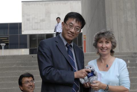 Kwong-loi Shun Poses with Colleague holding Stuffed Toy on H-Wing Patio Stairway, David Naylor in Background, Principal's Farewell Event for Kwong-loi Shun, H-Wing Patio