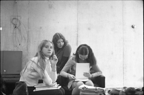 Three Seated Students Reviewing Papers