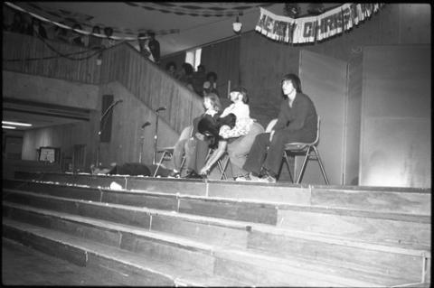 Four Students Seated and One Laying Down Onstage