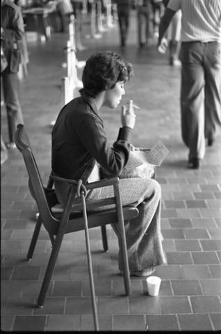 Student Seated on Chair Smoking and Reading Paper