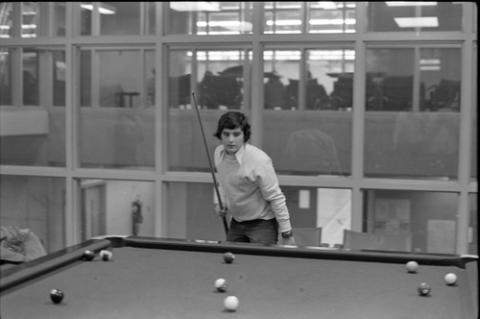 Student Playing Pool in Front of Windows