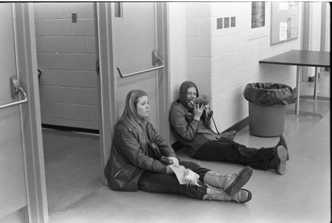 Two Students Sitting on Floor With Backs to a Door