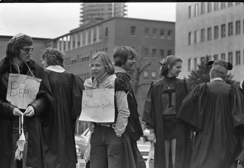 Students in Cloaks with Signs Around Necks