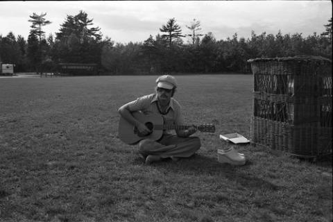 Student Seated with Guitar in a Field