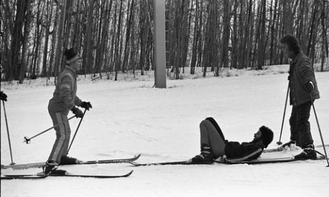 Two Students Sliding Towards a Third on Ski Hill